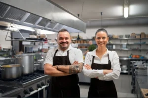Two chefs standing confidently with arms crossed in a professional kitchen