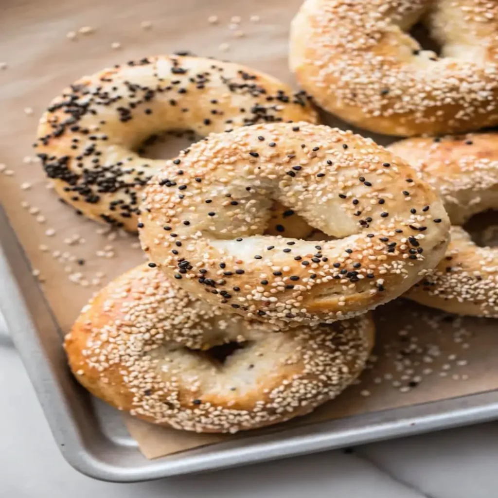 Unbaked everything bagel topped with sesame and poppy seeds on a white ceramic plate
