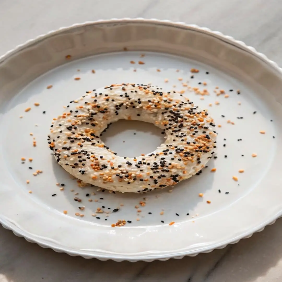 Close-up of freshly baked bagels with sesame and everything bagel toppings in a tray