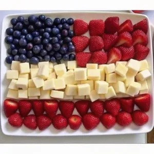 A top-down view of a white tray with blueberries in the corner and alternating horizontal rows of strawberries and cheese cubes.