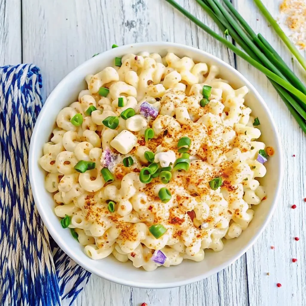 Overhead shot of a bowl of creamy pasta salad with elbow macaroni, paprika, and chopped scallions.