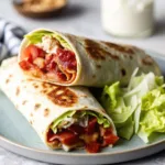 A stack of two grilled breakfast wraps filled with turkey bacon and salsa on a plate with a side of fresh salad.