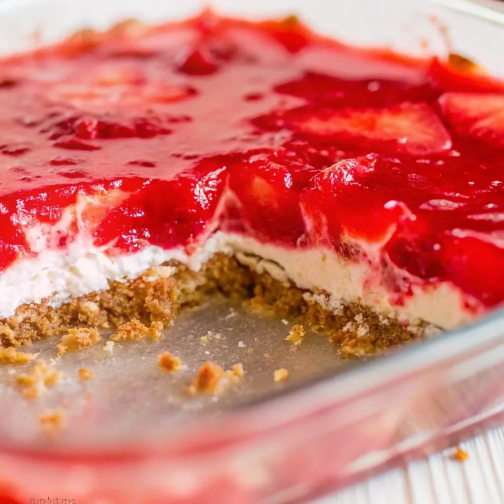 A high-angle close-up view looking into a glass pan of layered strawberry dessert.