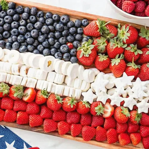 A wooden board featuring an American flag design made of blueberries, strawberries, and white marshmallows.