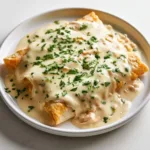 Plate of white chicken enchiladas topped with sauce and cheese