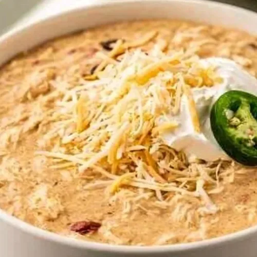 Chili 3 A bowl of spicy chili topped with cheese and herbs, showcasing vibrant flavors.