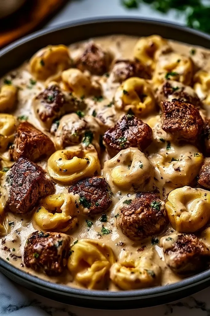 Creamy garlic steak tortellini served in a bowl garnished with fresh parsley