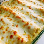 Delicious white chicken enchiladas topped with creamy sauce and garnished.